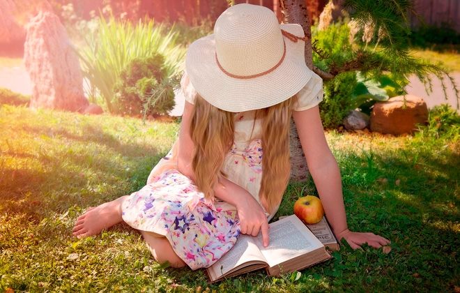 Девочка читает книгу на траве