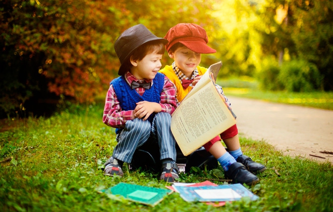 Мальчики читают книги на траве